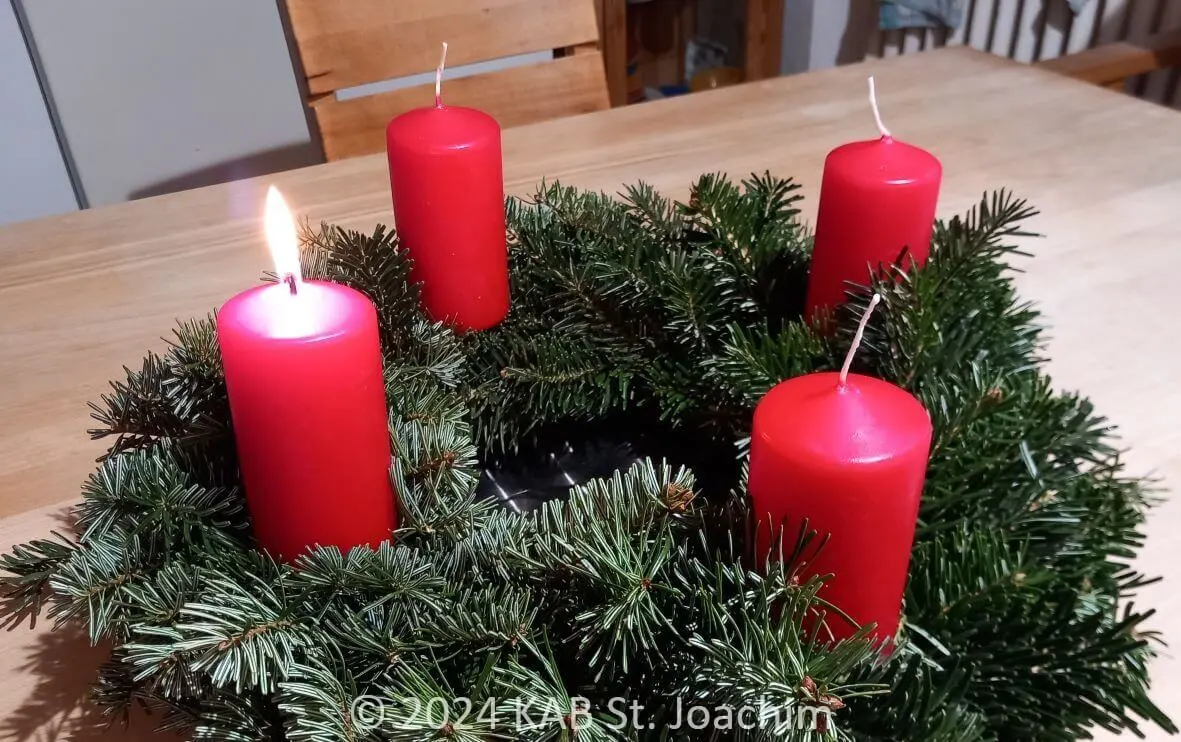 Adventskranz; die erste Kerze brennt.